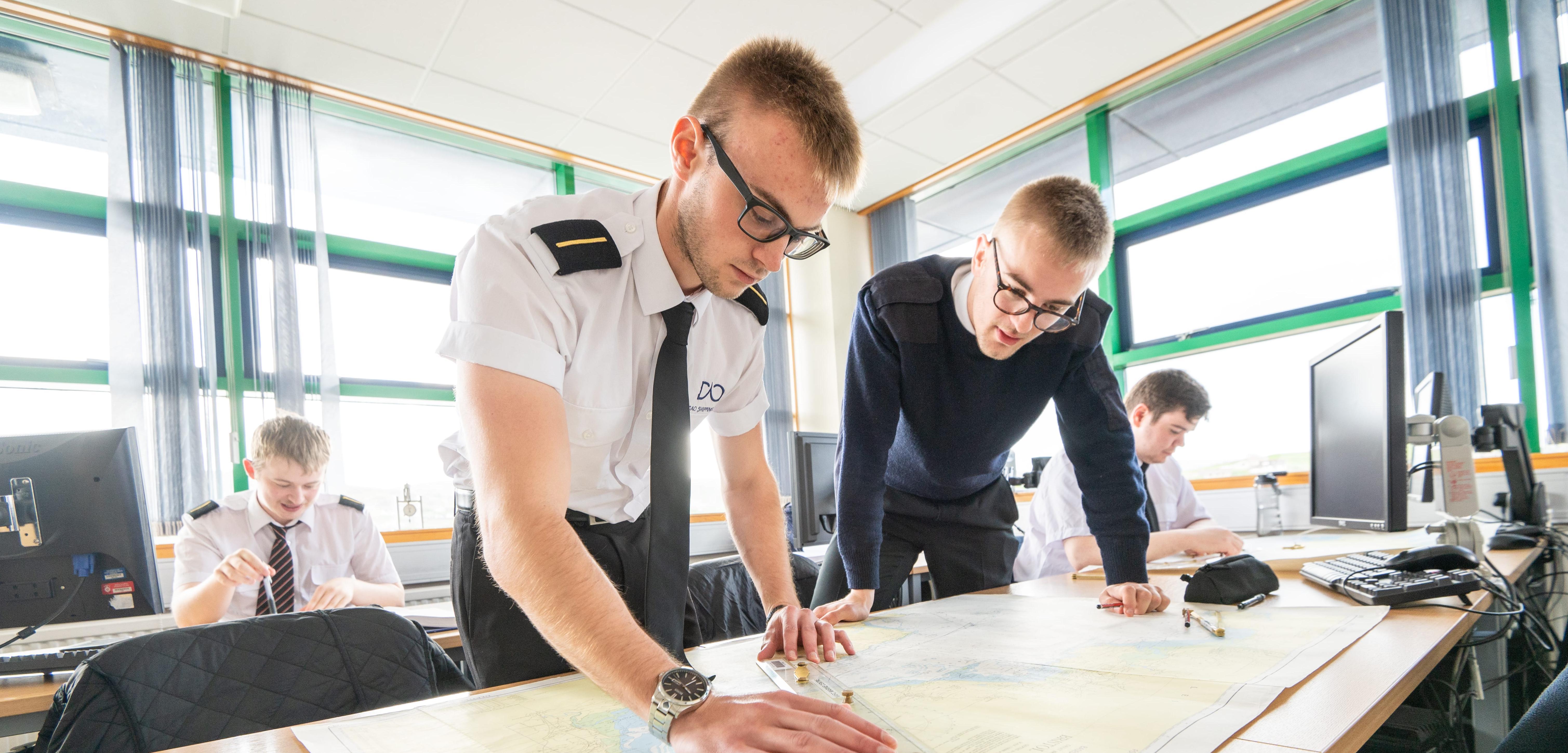 Merchant navy cadets looking at a sea chart Merchant navy cadets looking at a sea chart
