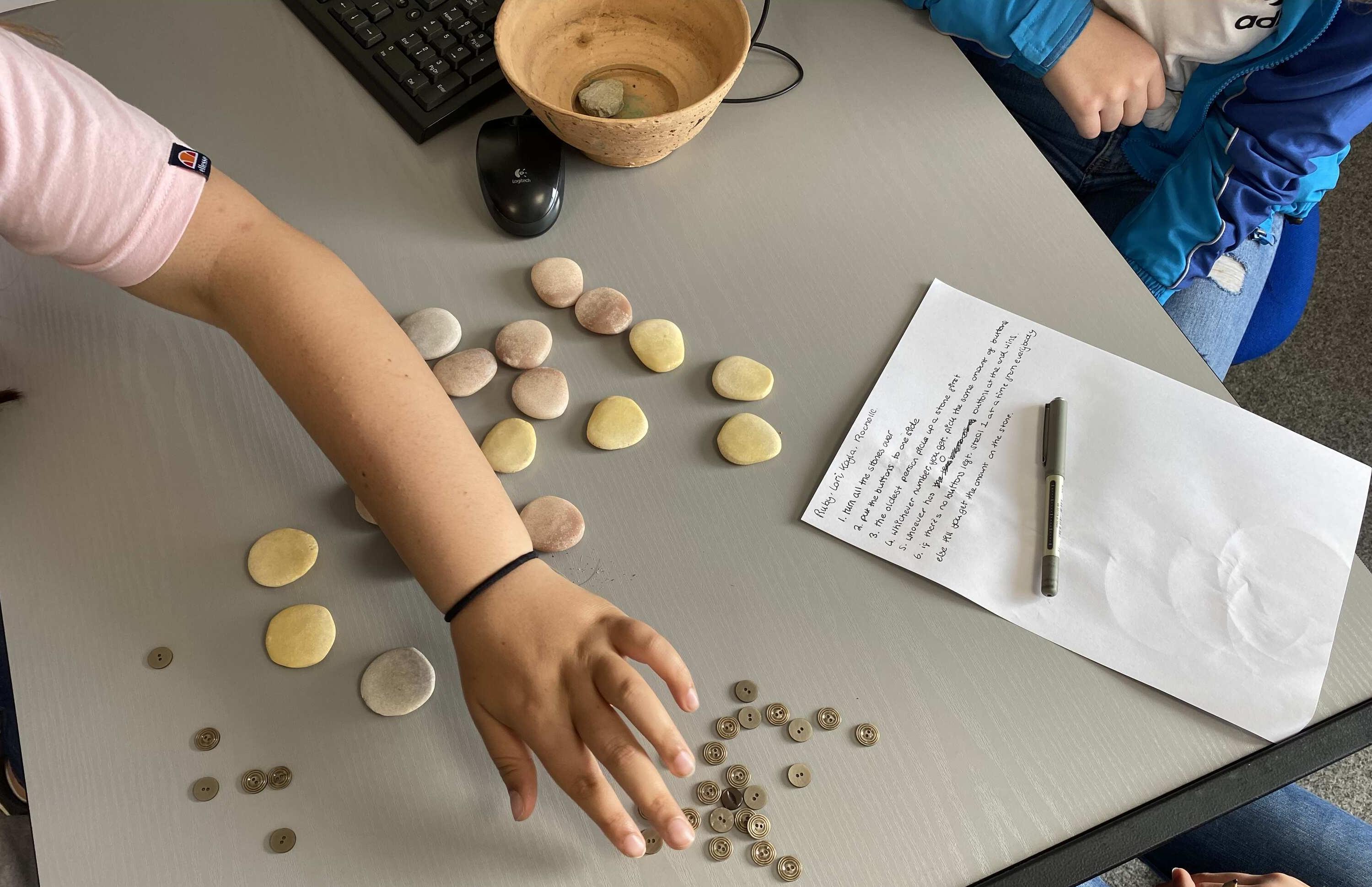 Childcare class learning with buttons and clay and a flowerpot piece of paper and pen