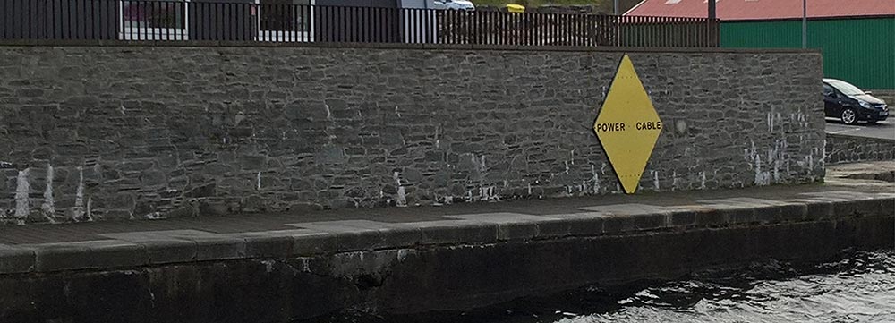 Power cable warning sign on wall above harbour