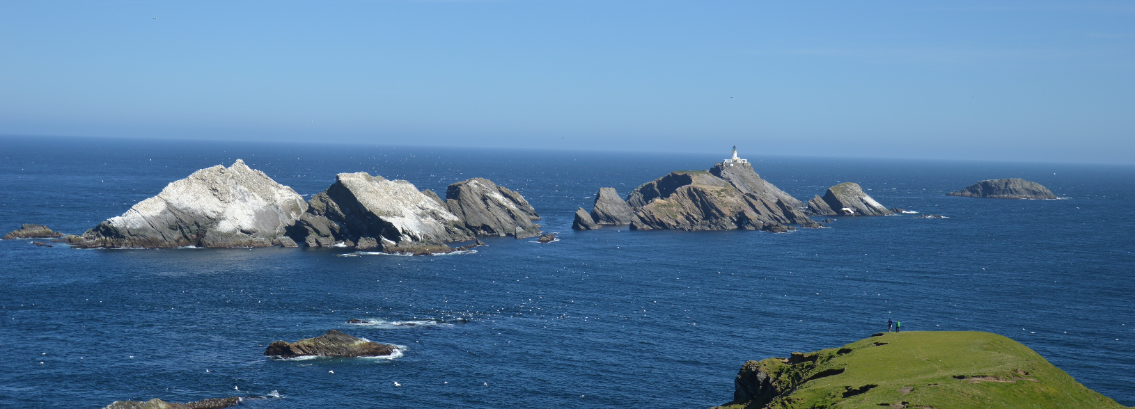 Large rocks off the coast one with a lighthouse Large rocks off the coast one with a lighthouse