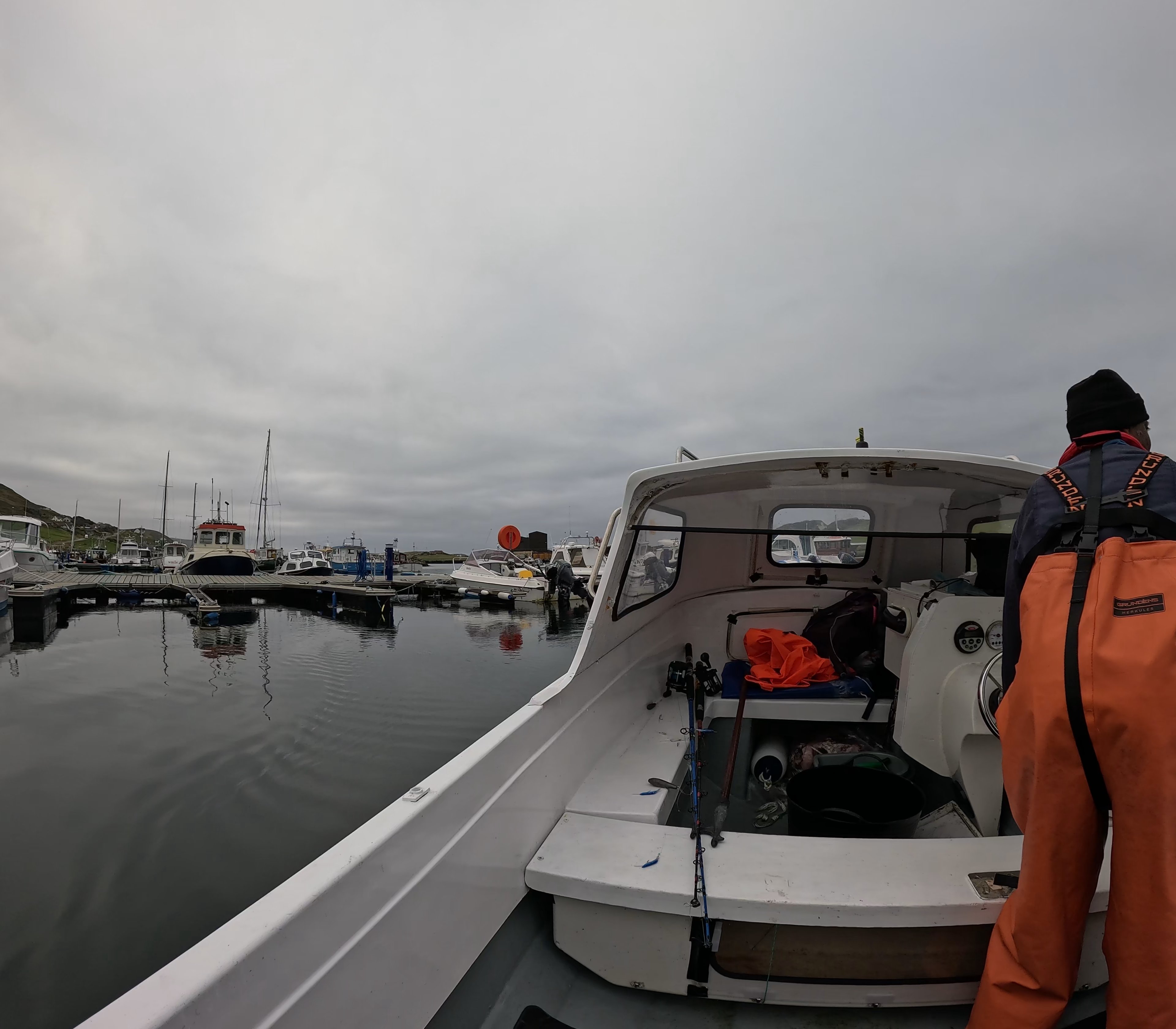 Man in overalls on small fishing boat leaving marina Man in overalls on small fishing boat leaving marina
